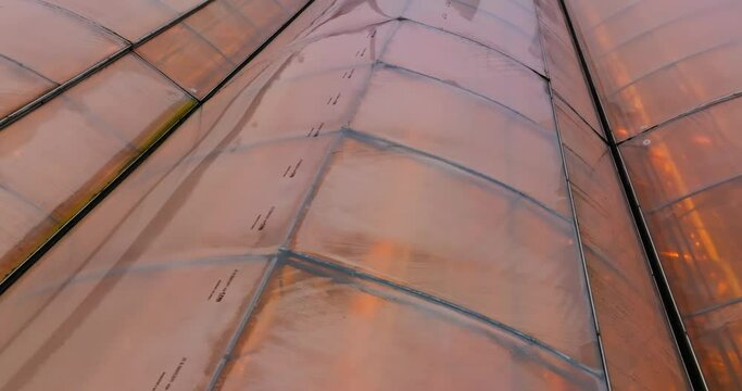 Aerial view around the glass roof of a heated greenhouse, on a gloomy winter day