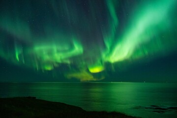 the aurora lights over water and land at night, from behind a cliff