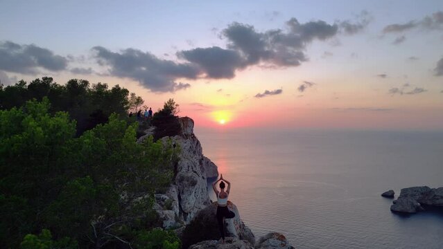 Wonderful aerial top view flight 
Ibiza cliff Yoga tree pose model girl sunset evening. static tripod hovering drone
4k cinematic