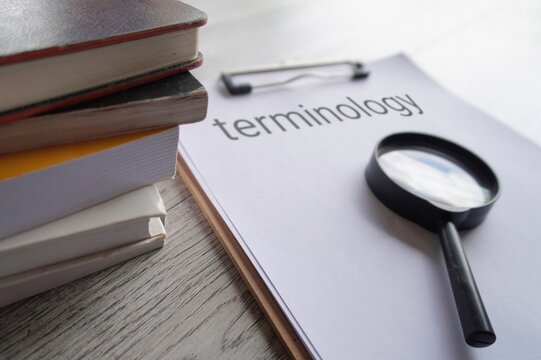 Closeup image of books, magnifying glass and paper clipboard with text TERMINOLOGY.