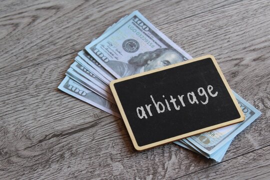 Closeup image of chalkboard with text ARBITRAGE and money. Business and financial concept.