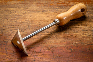 stainless steel shave hook scraper with wooden handle against grunge wood