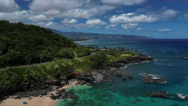 Waimea Bay, O'ahu, Hawaii during the day by a drone with wind turbines, churches, mansions, and rock