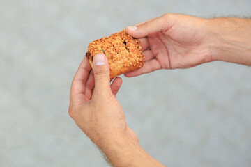 A guy's hand holds sweet pastry with jam, snack and fast food concept. Selective focus on hands with blurred background