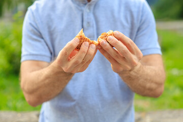 A man's hand holds sweet pastry with jam, snack and fast food concept. Selective focus on hands with blurred background