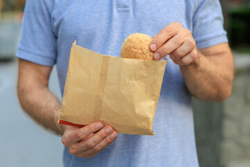 Man's hand holds mini bread, snack and fast food concept. Selective focus on hands with blurred...