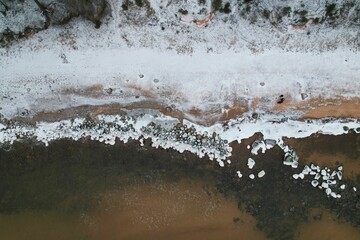 Aerial view of a beach with a thick layer of frosty ice covering the sand