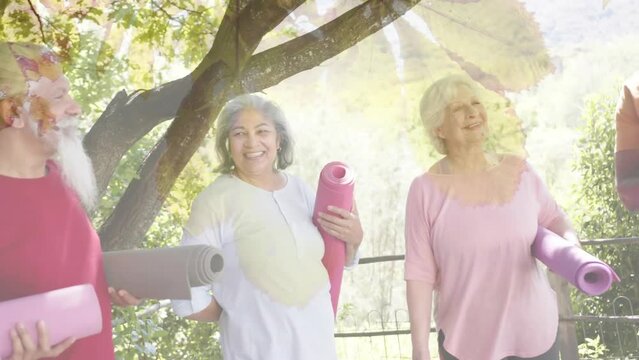 Animation of spots of light and trees over diverse senior people with yoga mats in garden