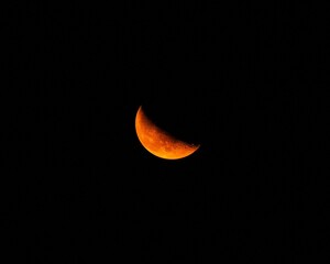 Picturesque view of a glowing orange crescent moon set against a night sky