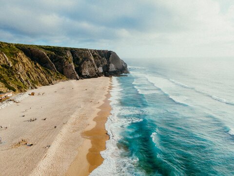 Picturesque beach with a serene ocean backdrop, featuring a dramatic rocky cliff-face