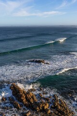 Closeup of a Seascape sunrise with waves rolling in and rocky foreground.