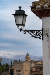 Fototapeta na wymiar Alhambra palace view with snowy mountains and a street lamp in the foreground.