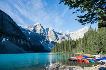 Scenic Morraine lake surrounded by mountains featuring several colorful canoes in Banff, Canada