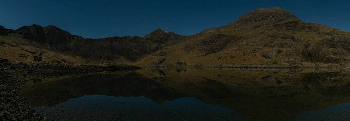 Fototapeta na wymiar Awe-inspiring aerial view of a tranquil lake surrounded by majestic mountains: Snowdon Pano at night
