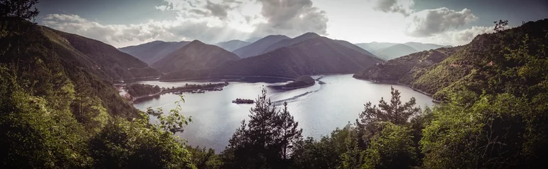 Foto op Canvas Breathtaking landscape of a tranquil lake surrounded by majestic mountains and lush evergreen trees © Wirestock