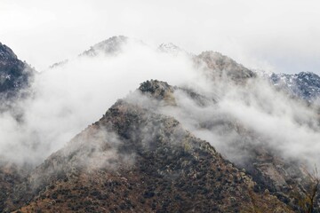 Majestic mountain peak shrouded in wispy clouds and fog.