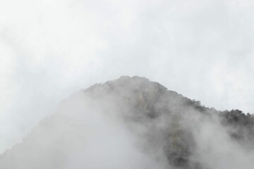 Majestic mountain peak shrouded in wispy clouds and fog.