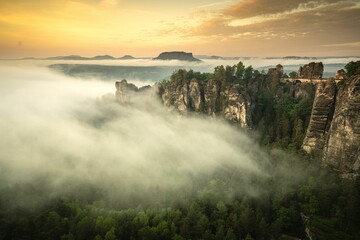 Vibrant sunrise with a foggy spectacle amid majestic mountain ranges and rocky formations.
