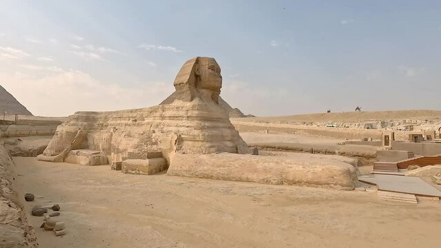 Pan across iconic sphinx in egypt at midday, historic excavation site of a grand wonder