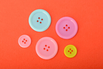 Pink, blue and yellow sewing button isolated on a red background.