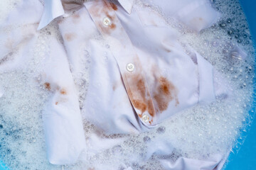 Dirty choclate stain on white shirt soaking in water with detergent water dissolution, washing cloth