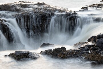 Obraz premium water running down a rock face with rocks in the foreground