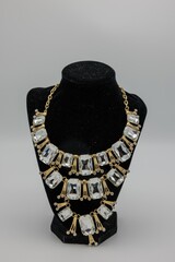 Luxurious gold necklace with sparkling crystals draped around a mannequin neck