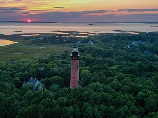Aerial view of Currituck Beach Lighthouse on an island surrounded by lush green trees - Powered by Adobe