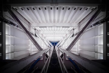 Person standing inside a symmetrical man-made interior walkway with multiple levels and floors