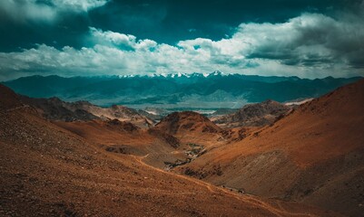 the landscape is full of mountains and clouds above them, while a lone road winding