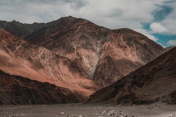 a brown and red mountain range under a blue cloudy sky
