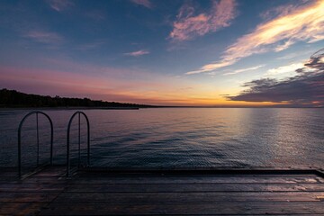 Fototapeta premium an empty dock on a body of water under a sunset