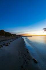 sunset at a beach with a few people walking on it