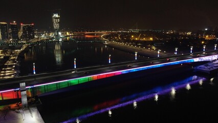 Fototapeta premium Scenic nighttime view of Belgrade Branko bridge over water, with cars seen driving across
