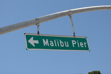 Green and white street sign pointing to Malibu Pier in California
