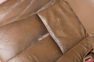 close-up of used worn and torn leather car seat, beige seat with wear and tear, including scuffs,...