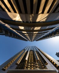 Fototapeta premium Low-angle shot of modern buildings with multiple windows reflecting the blue sky.