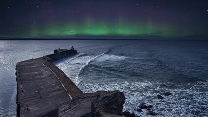 Captivating view of a majestic aurora dancing in the night sky over a long bridge on the seashore
