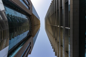 Low-angle shot of modern buildings with multiple windows reflecting the blue sky.