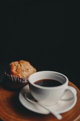 Vertical shot of a cup of hot coffee and a sweet cookie on the wooden surface