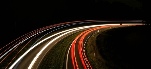 Aerial long-exposure view of car light trails on a highway road at night