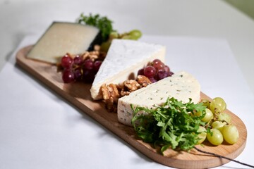 Wooden tray filled with an assortment of fresh grapes and various types of cheese