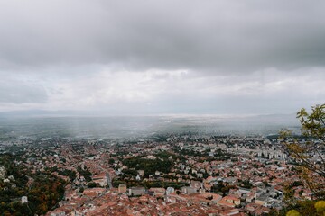 Aerial shot of the cityscape of Brasov, Romania under a cloudy sky.