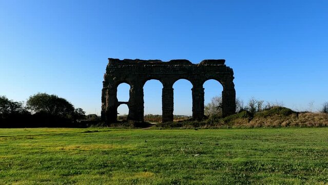 Flock of brds flying on grass lawn near Claudio aqueduct
landmark in Rome, Italy wuth blue sky