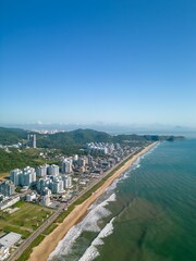Fototapeta premium Aerial view of a beach and Praia Brava cityscape in the background under the blue sky