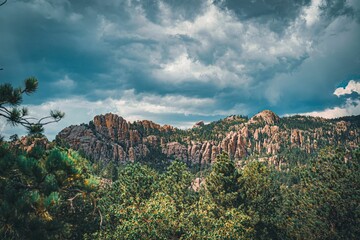a mountain covered in trees with storm clouds above it - image gratf