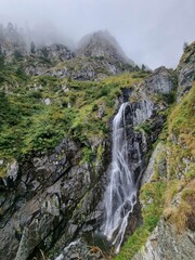 Fototapeta na wymiar a tall waterfall flowing down a lush green hillside side with vegetation