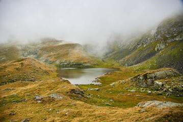 Breathtaking view of a glacial lake in the Fagaras Mountains surrounded by lush hills