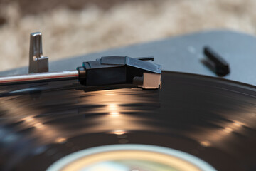 Close up of a vinyl record spinning on a turntable with light reflections accenting the surface of...