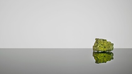 Pyrite rock crystal with its reflection against a grey background.
